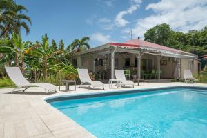 - une piscine avec des chaises et une maison dans l'établissement Hôtel Les Bananiers, au Gosier