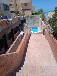 エル・アラメインにある6B Basement chalet 114 4 beds 2 bathrooms on the pool green beachのスイミングプールの横のレンガ造りの壁