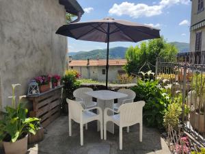 una mesa, sillas y una sombrilla en el patio en Casa all'era en Cernobbio