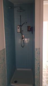 y baño con ducha y pared de azulejos azules. en Mansarda Marinello, en Oliveri