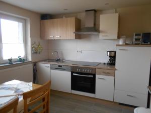 a kitchen with white appliances and a table and a window at Ferienwohnung-Pension Werrablick in Witzenhausen