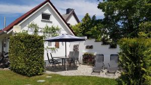 a white house with a table and chairs and an umbrella at Ferienhaus Ostseebrise Usedom im Grünen familienfreundlich ruhig Parkplatz Terrasse Kamin in Ostseebad Karlshagen