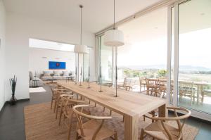 een lange houten tafel en stoelen in een kamer met ramen bij Villa Miramar by Glasir in Sitges
