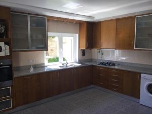 a kitchen with wooden cabinets and a sink and a window at Room solo - Villa Ribeiro On Way to Santiago with Secure Bike Garage - Esposende in Esposende