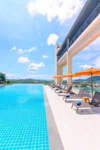 a pool at a hotel with chairs and umbrellas at Hilltop Wellness Resort in Phuket