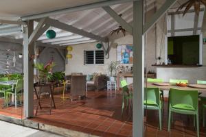 a kitchen and dining room with green chairs and tables at Hôtel Les Bananiers in Le Gosier