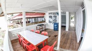 a dining room with a table and red chairs at Nias Surf Stay in Lagudri