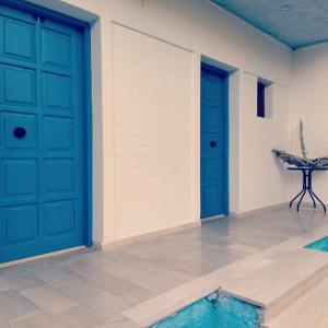 Filoxenia Apartments في Rizá: غرفة ذات بابين زرقين وحمام سباحة