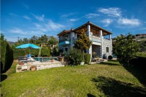 una casa con un grande cortile con un ombrellone di Kelly's Villa in Stoupa a Neokhórion