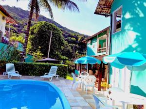 阿布拉奥Pousada Anambé的房子旁边有带椅子和遮阳伞的游泳池