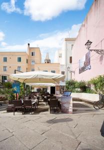 a patio with tables and chairs and an umbrella at Alghero Gilbert Ferret in Alghero