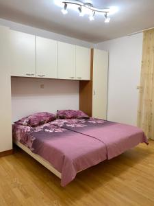 a bedroom with a large purple bed with white cabinets at Apartments Marina in Rab