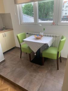 eine Küche mit einem Tisch und grünen Stühlen in der Unterkunft apartman Fuerte 2 in Belgrad