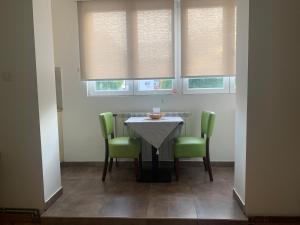 een eetkamer met een tafel en groene stoelen bij apartman Fuerte 2 in Belgrado