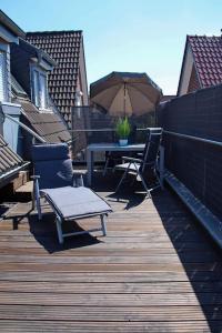 eine Terrasse mit einem Tisch, Stühlen und einem Sonnenschirm in der Unterkunft Ferienwohnung Auf der Blumenstrasse in Nettetal
