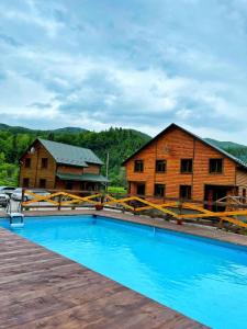 a resort with a blue pool in front of a building at Villa Na uzlissi in Migovo