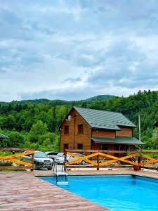 a house with a pool in front of a building at Villa Na uzlissi in Migovo