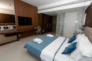 a bedroom with a large bed with blue pillows at Empire Beach Resort ADULTS ONLY in Dhërmi