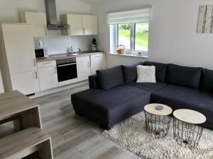 sala de estar con sofá negro y cocina en Ferienwohnung Stafflel - Wohlfühlen im Odenwald, en Schmal-Beerbach