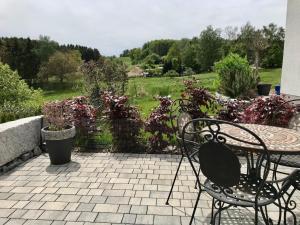 Un patio con mesa y sillas y flores. en Ferienwohnung Stafflel - Wohlfühlen im Odenwald, en Schmal-Beerbach