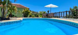 Una piscina con una sombrilla al lado de una casa. en Finca Villa Arriba, en Arecida