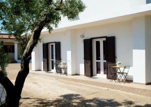 un edificio bianco con porte nere e un albero di Alloggi in Villa Potenza a pochi minuti da Gallipoli a Galatone