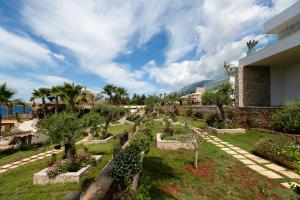 a garden in front of a building with trees and bushes at Empire Beach Resort ADULTS ONLY in Dhërmi