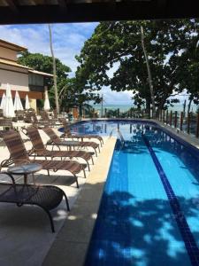 a swimming pool with chaise lounge chairs next to it at Porto Praia do Forte in Praia do Forte