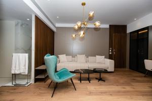 a living room with a white couch and a blue chair at Empire Beach Resort ADULTS ONLY in Dhërmi