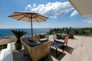 a patio with chairs and an umbrella and the ocean at Empire Beach Resort ADULTS ONLY in Dhërmi