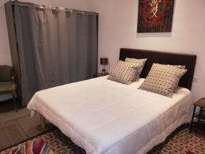ein Schlafzimmer mit einem großen Bett mit weißer Bettwäsche und Kissen in der Unterkunft LA MAISON DU BIEN ETRE o in Alès