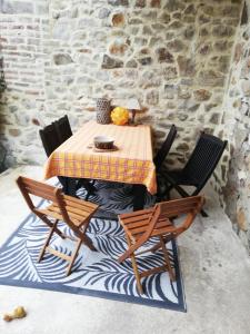 einen Tisch und Stühle mit einem Tisch und einer Steinmauer in der Unterkunft LA MAISON DU BIEN ETRE o in Alès