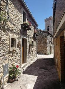 an alley in an old stone building with flowers at Helikon -la dimora del viandante- in Montalbano Elicona