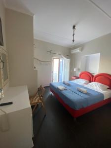 AEGEAN VIEW SEASIDE ROOMS AND STUDIOS KEA في Korissia: غرفة نوم مع سرير وكراسي حمراء ومكتب