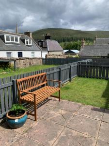 a wooden bench sitting on a patio next to a fence at Pannanich View Cottage, Ballater in Ballater