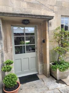 a door to a house with two potted plants at Wee Grange in Bath