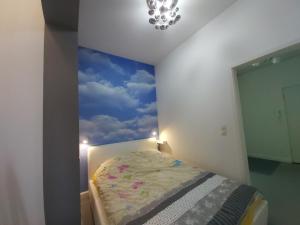 a bedroom with a painting of a blue sky at Apartment for you 2 Królewiecka 21 in Mrągowo