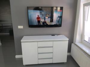 a white dresser with a flat screen tv on a wall at Apartment for you 2 Królewiecka 21 in Mrągowo