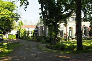 Zuidhorn的住宿－De oude dokterspraktijk，前面有树木的大白色房子
