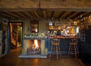 a bar with a fireplace in the middle of a room at The Anchor Inn in Lower Froyle
