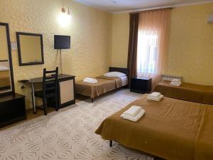 アルヒーポ・オシポフカにあるGuest House Adelのベッド2台とデスクが備わるホテルルームです。