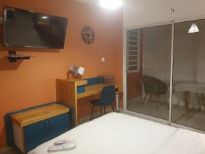 a room with a bed and a desk and a tv at Yangou Appart 1 in Mamoudzou