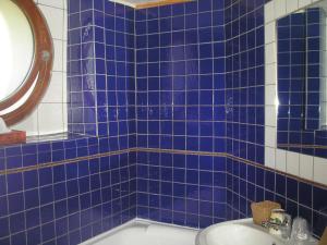 baño de azulejos azules con lavabo y bañera en La Pastorale en La Bâtie-Neuve