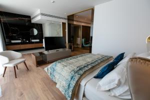 a bedroom with a large bed and a television at Empire Beach Resort ADULTS ONLY in Dhërmi