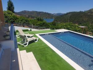 a swimming pool with a chair and a lawn at Casa do Barco in Pombeira