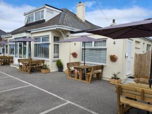 een patio met houten tafels en banken voor een gebouw bij Tregarthen - Adult Only in Newquay