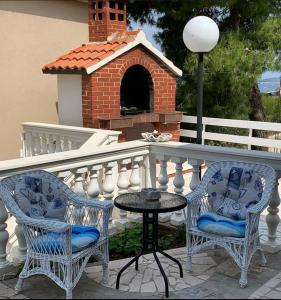 two chairs and a table on a balcony with a brick oven at Apartments Neda in Primošten