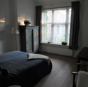 a bedroom with a bed and a large window at De oude dokterspraktijk in Zuidhorn