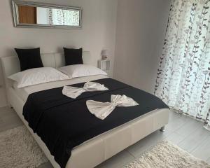 a bedroom with a large bed with black and white sheets at Apartments Neda in Primošten