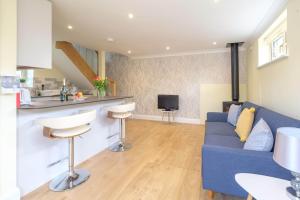 uma sala de estar com um sofá azul e uma cozinha em Foxes Lodge em Aldringham